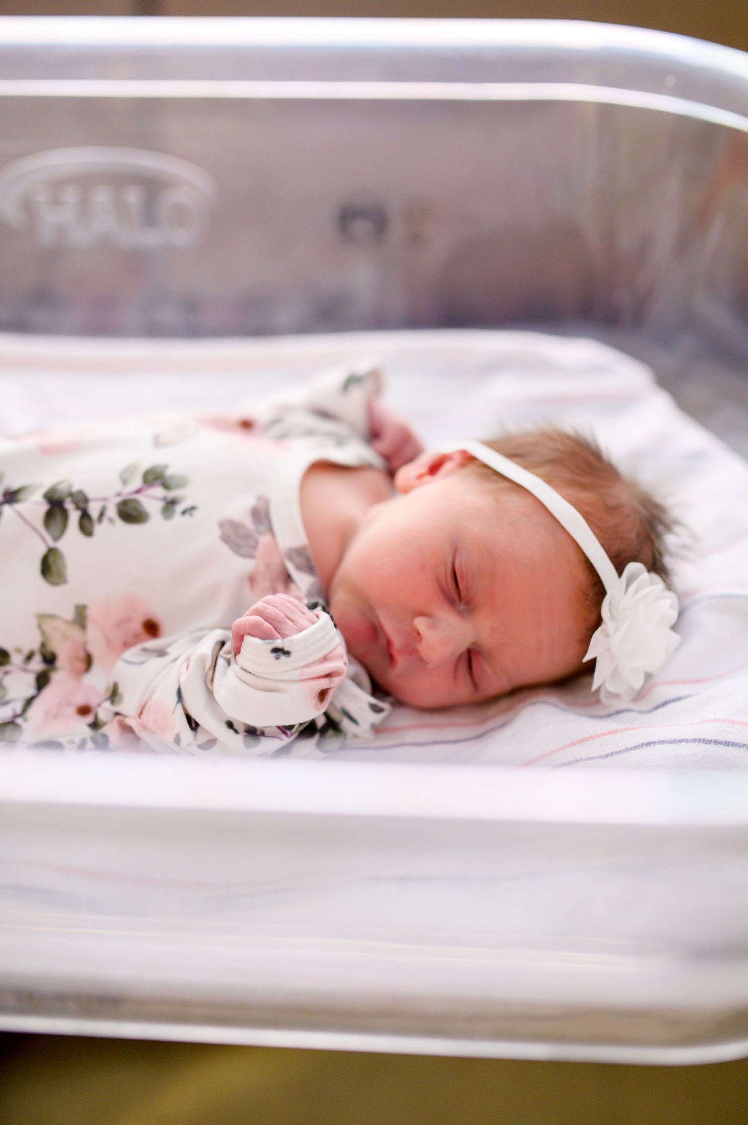 A sleeping newborn baby wearing a floral outfit rest peacefully in a UT hospital bassinet in Knoxville, TN