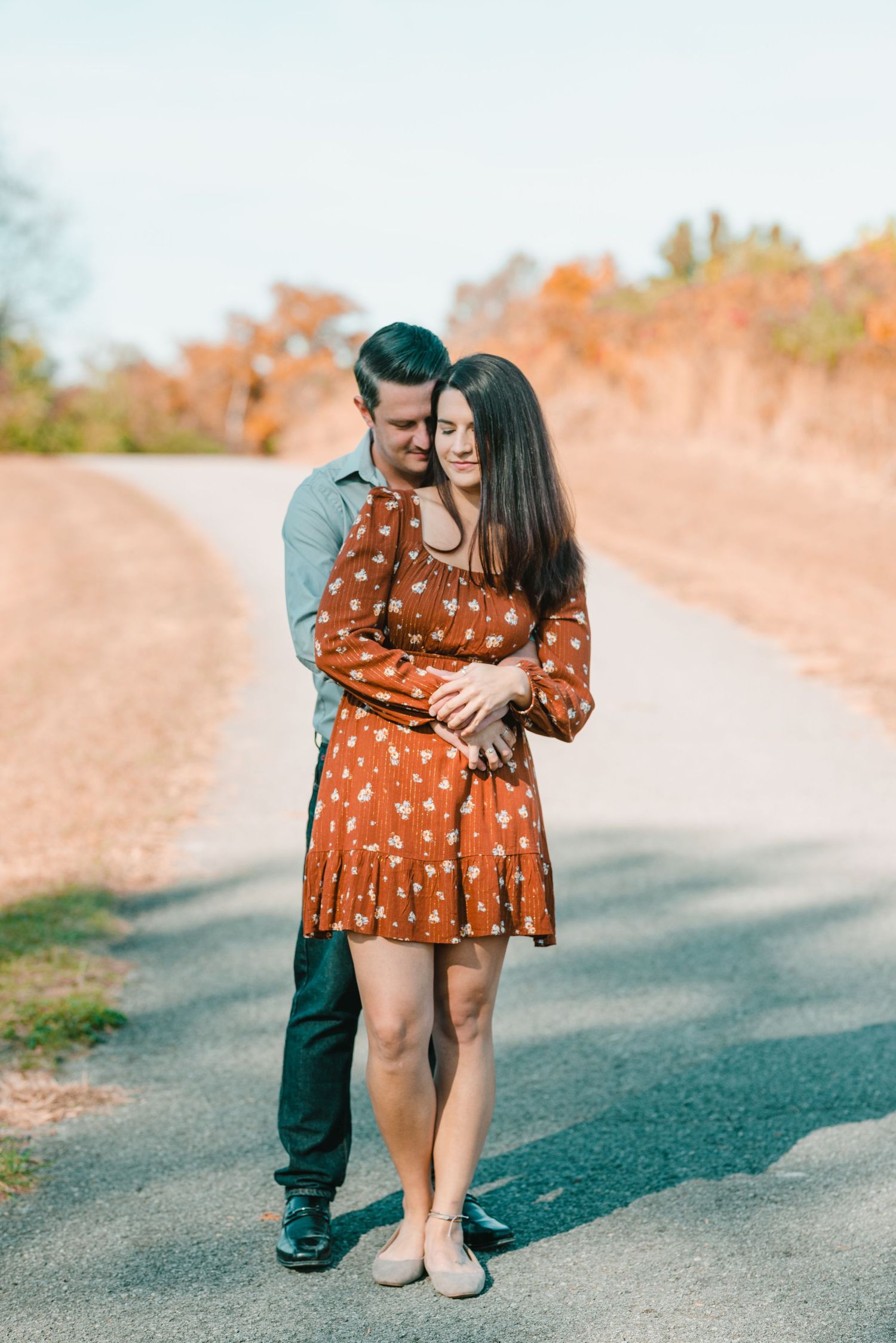 A couple embraces tenderly on a path surrounded by fall foliage. Knoxville Couple Photographer