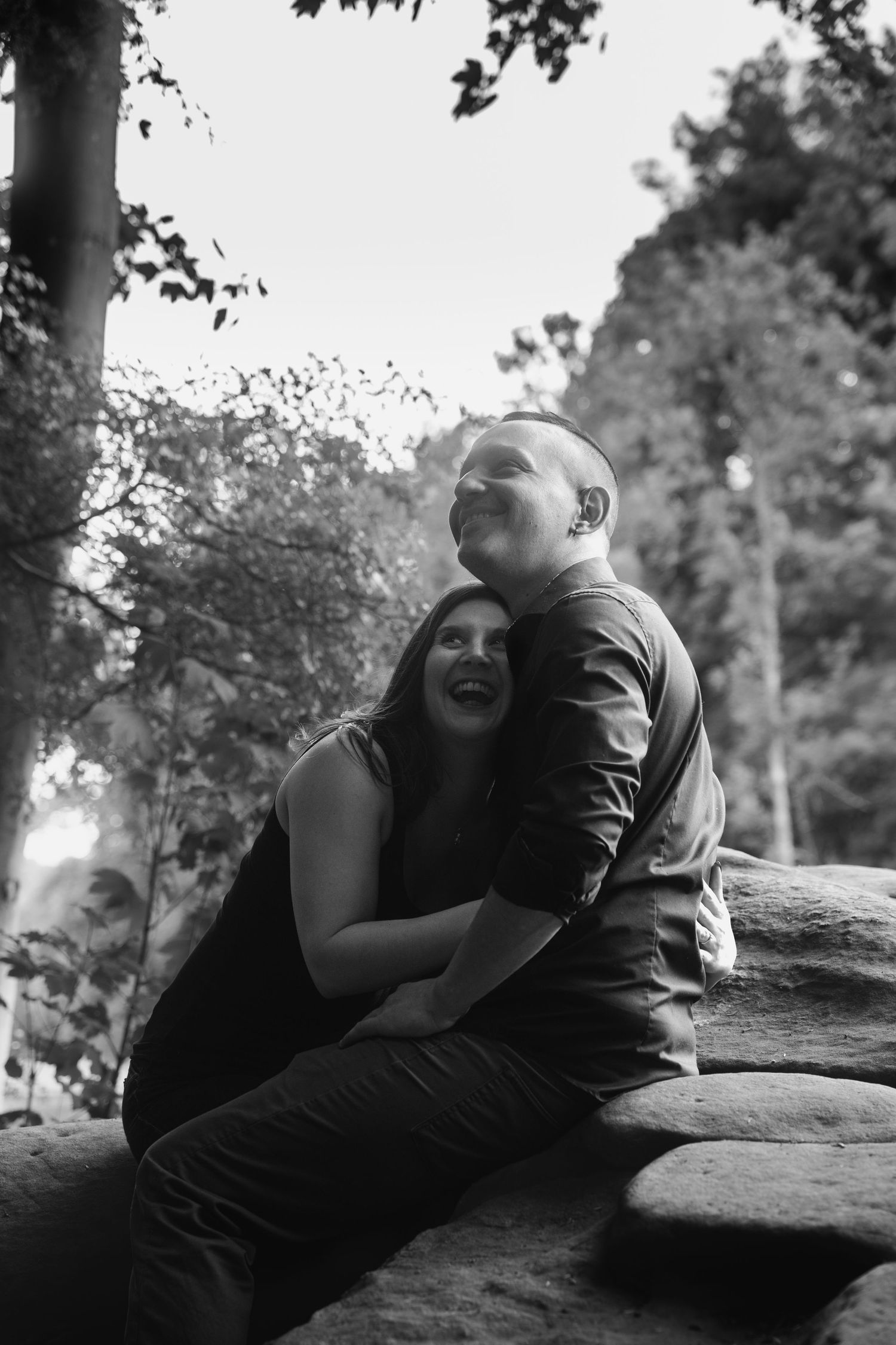 Une photo en noir et blanc d'un couple partageant un moment de jeu sur un rocher à l'extérieur.