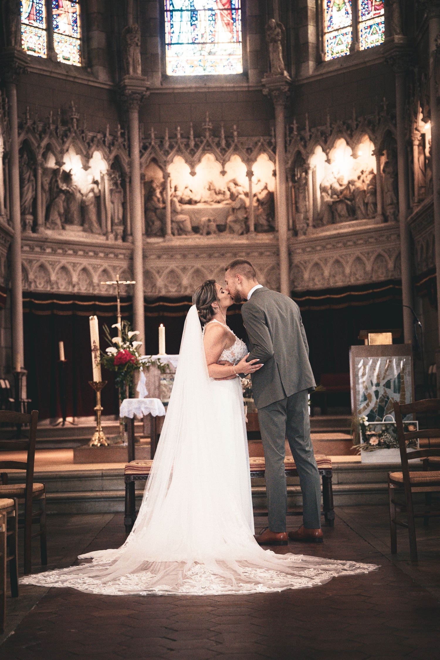 Un couple partage un moment doux dans une grande cathédrale avec des vitraux et une architecture gothique.