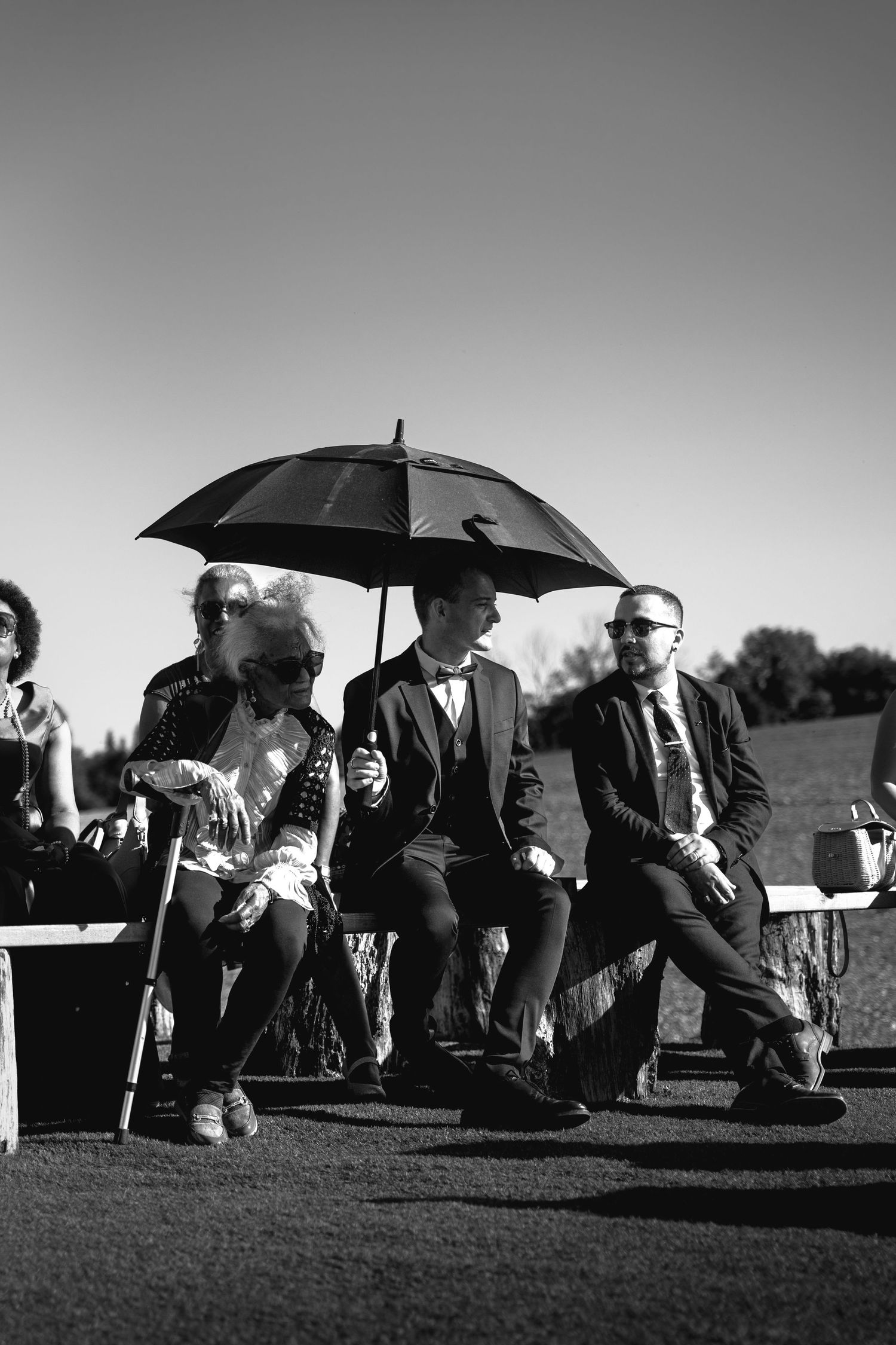 Une photo panoramique en noir et blanc montre la famille avec des parapluies rassemblés à l'extérieur sur un flanc de colline.
