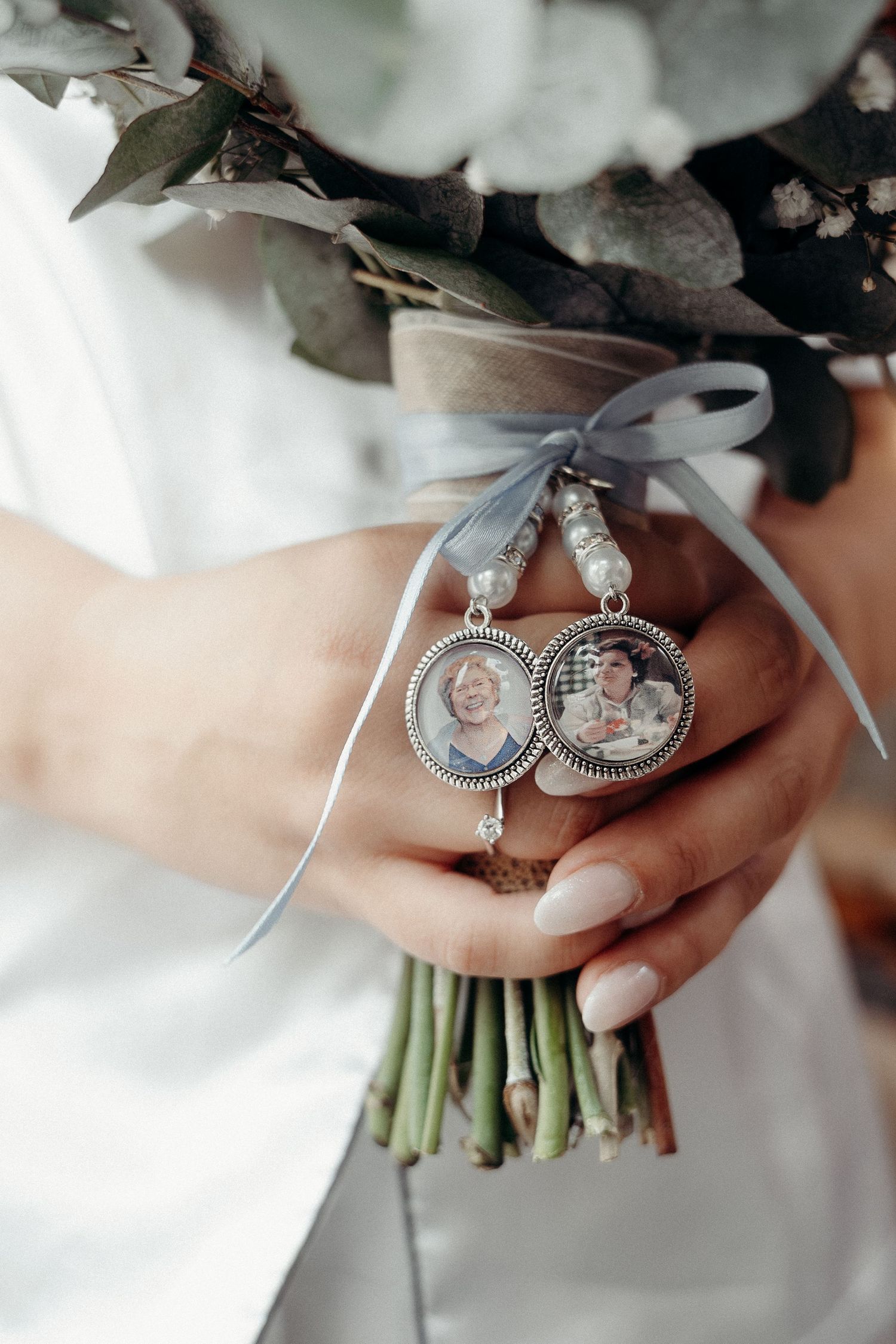Close-up details of vintage silver earrings held against a white dress and floral bouquet.