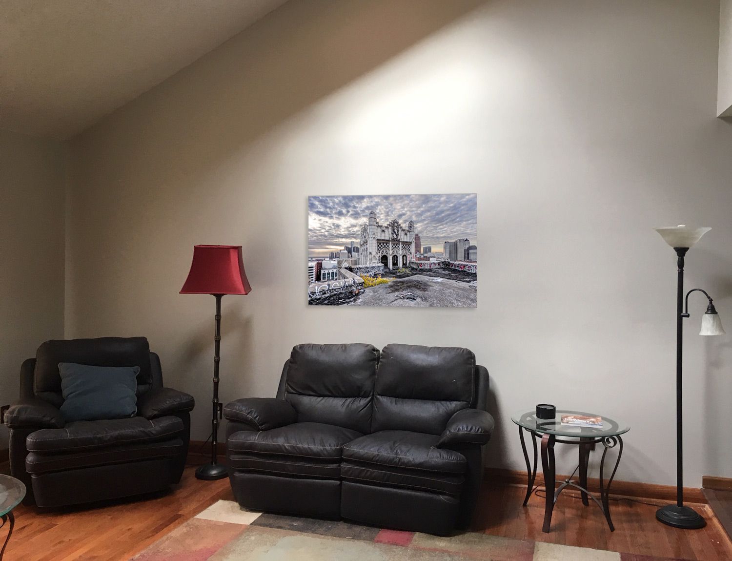 Living room interior with black leather couch and chair showcases photo of the Metropolitan building in Detroit, Michigan.