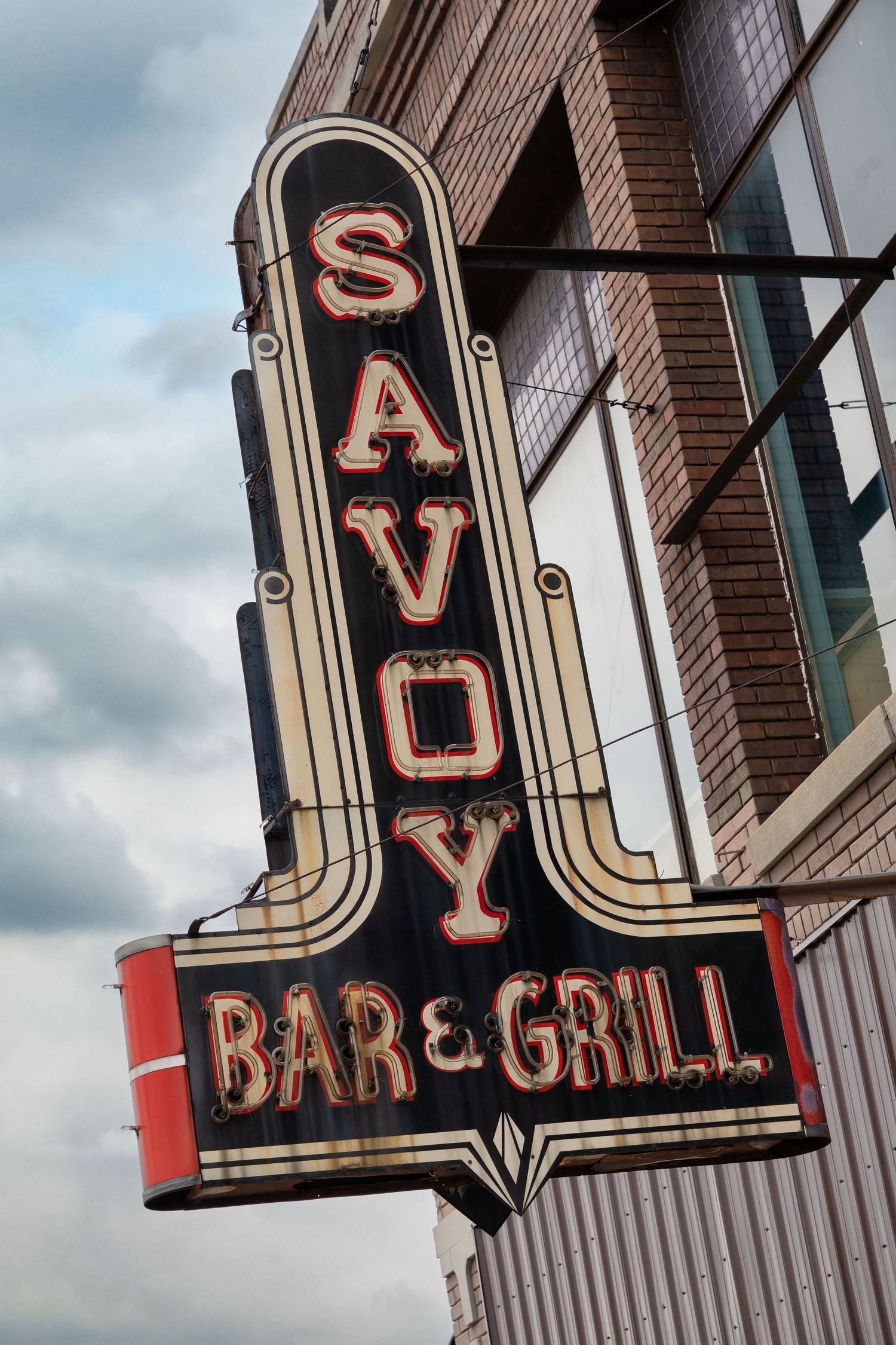 Vintage Savoy neon bar and grill sign with art deco styling mounted on brick building facade in Saginaw, Michigan.