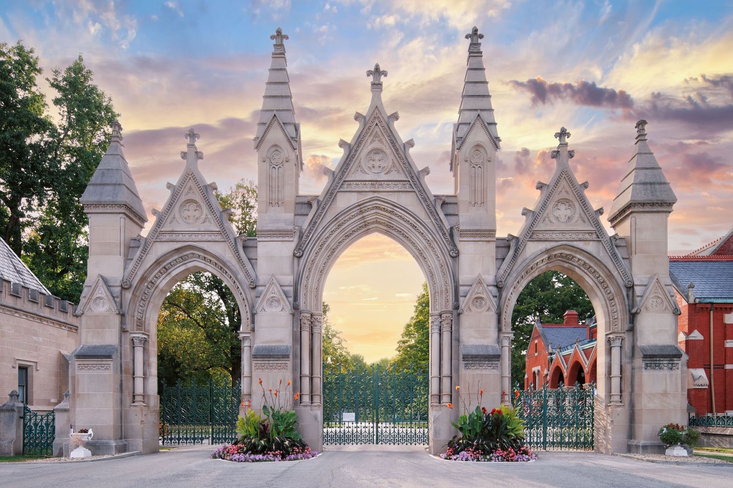 Gothic stone entrance gate with ornate arches and decorative spires at sunset at Crown Hill Cemetery in Indianapolis, Indiana.