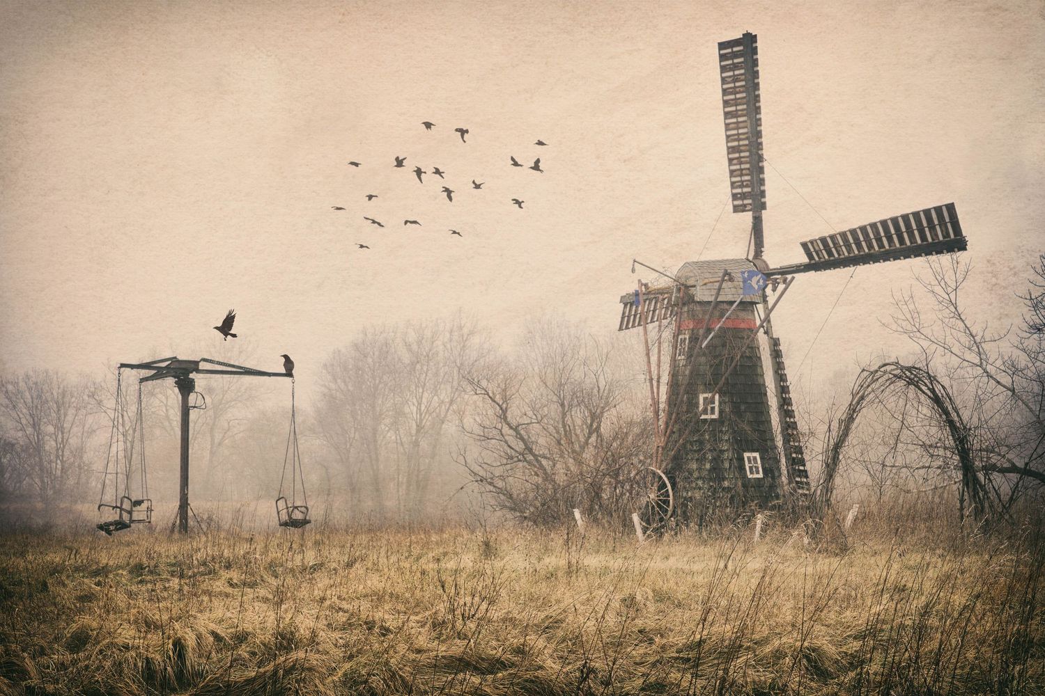 Misty abandoned rural landscape scene in Michigan with windmill, swings and birds flying with sepia tones.