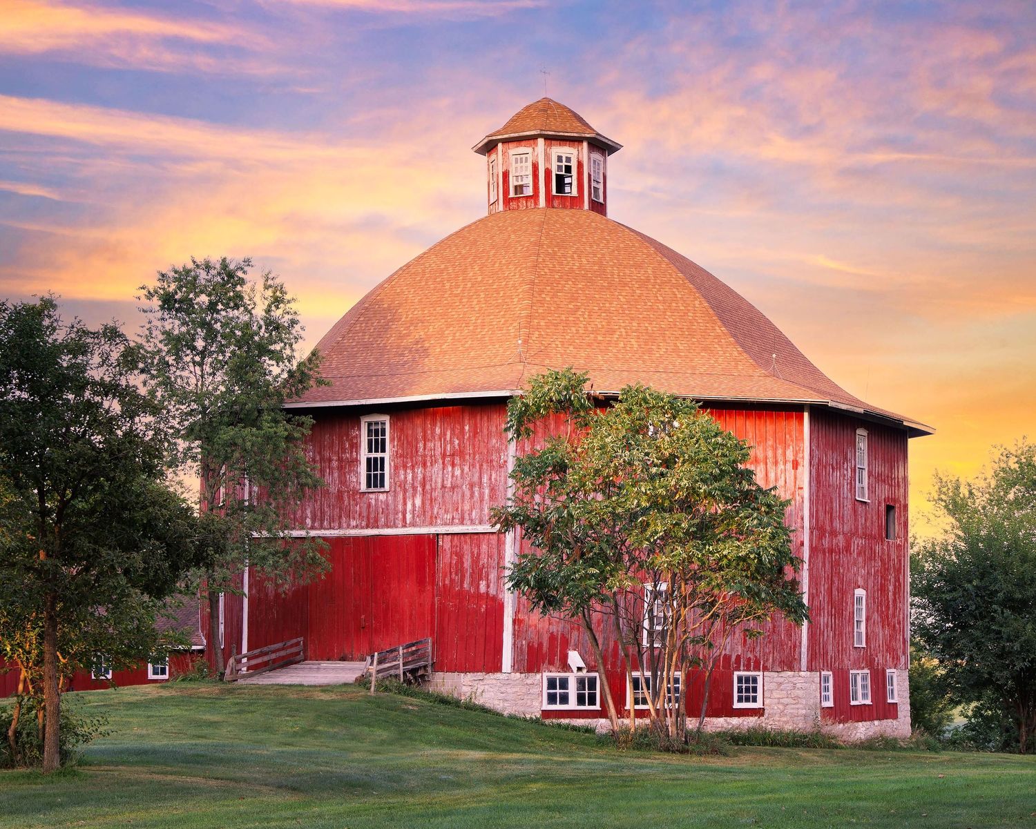 Secret 1883 octagon barn photographed at sunset with golden sky in Johnson County Iowa.