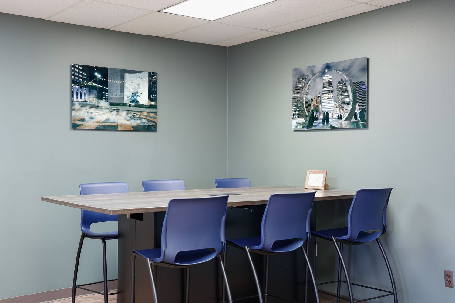 Modern office break room with blue chairs and scenic wall art.