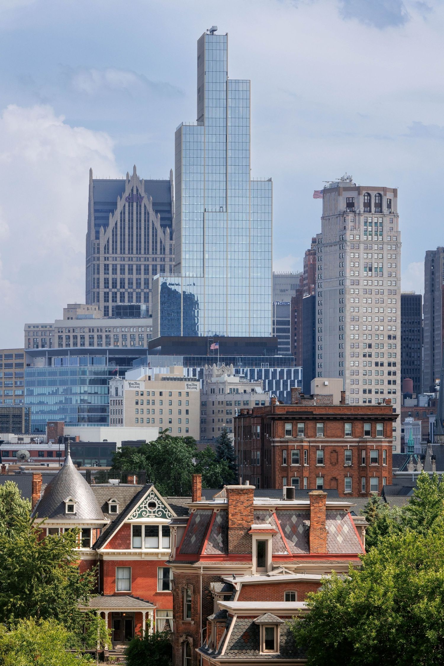 Modern glass skyscrapers rise above historic red brick buildings in Boston's downtown skyline on a sunny day.
