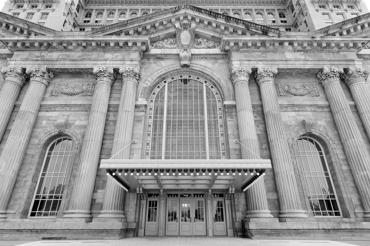 Black and white photo of the Michigan Train Station renovated entrance with ornate columns, arched windows and marquee.