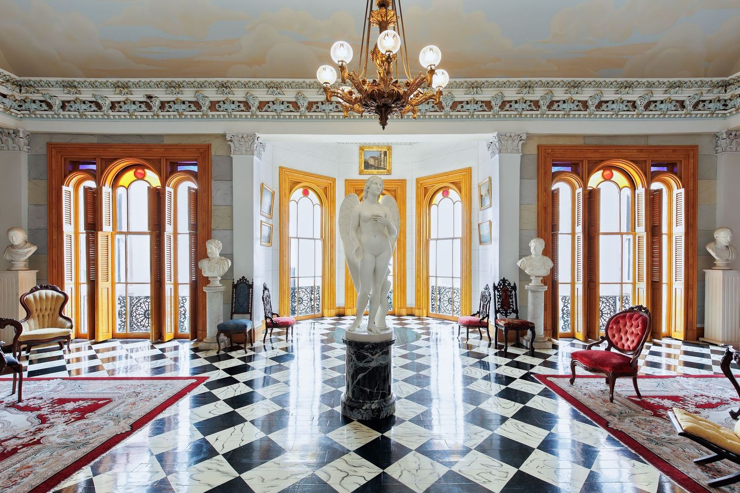 Luxurious interior salon with marble floors, chandelier, a statue and busts at the Belmont mansion in Nashville, Tennessee.