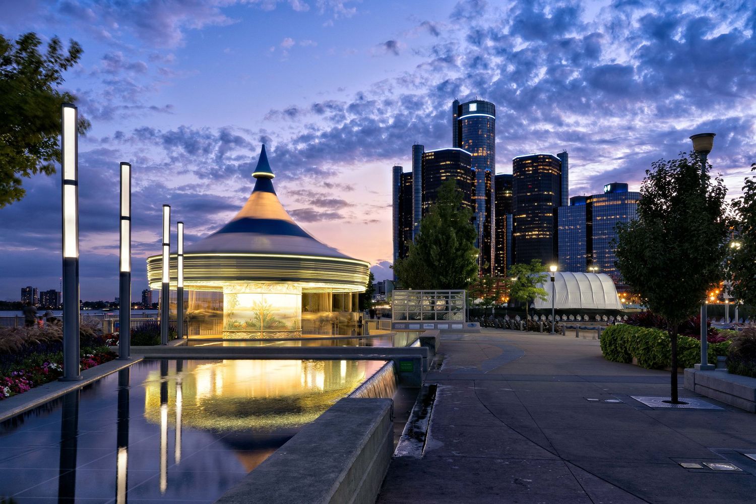 Lighted carousel at dusk in motion with dramatic blue cloudy sky at the Cullen plaza along the riverfront in Detroit Michigan.