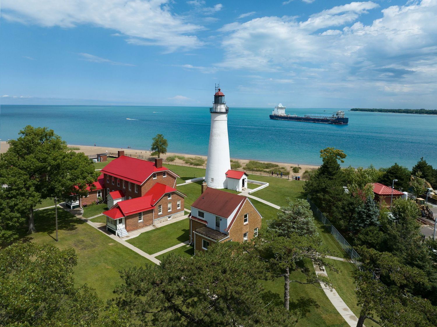 Fort Gratiot Lighthouse with a freighter on Lake Huron along a scenic Great Lakes coastline in Port Huron, Michigan captured with drone.