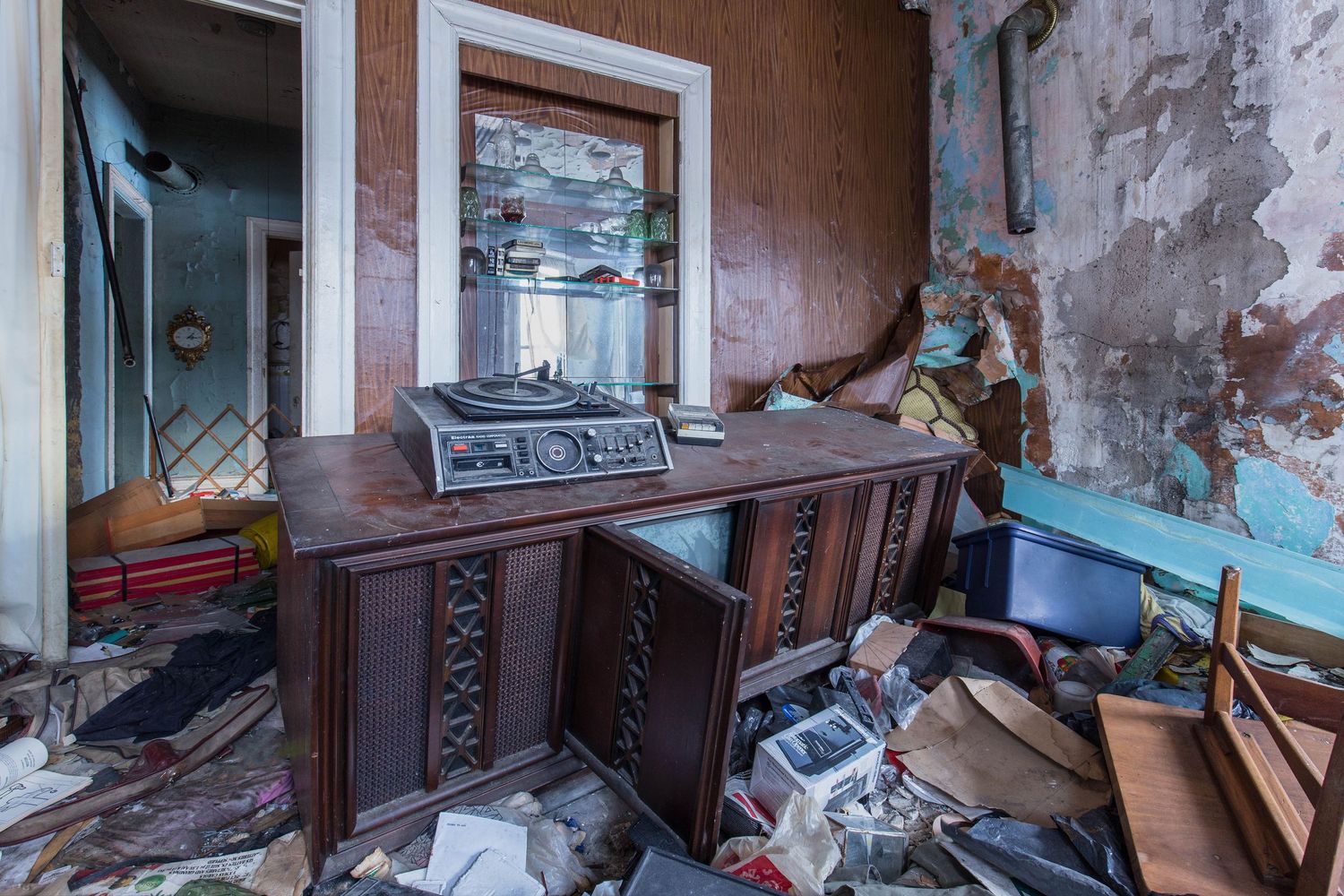 Abandoned interior living room with peeling walls and scattered debris in an abandoned home in Detroit, Michigan.
