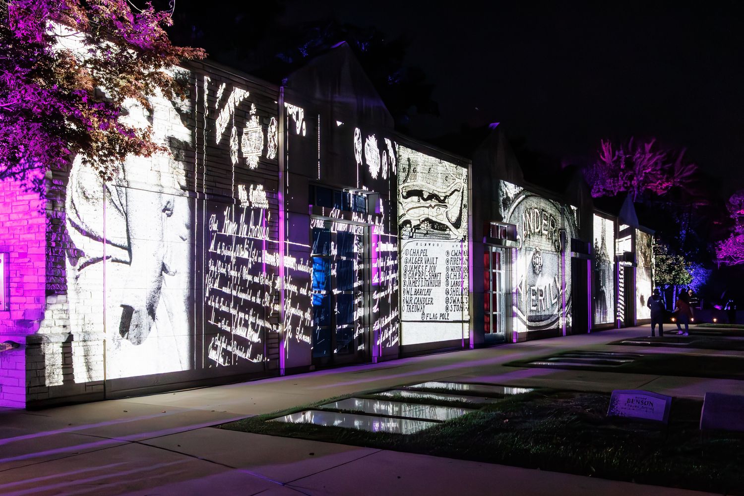 Illuminated mausoleum slideshow with purple and white lighting creating a dramatic nighttime atmosphere at Elmwood Cemetery in Detroit.