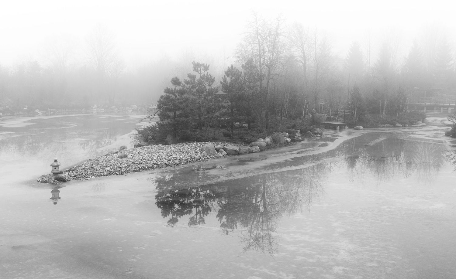 Tranquil winter lakeside view with mist rising over the water and shoreline at the Frederick Meijer Gardens in Grand Rapids, Michigan.