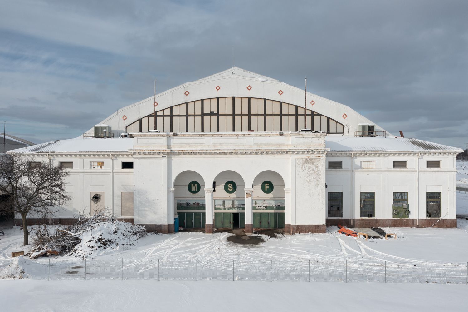 Snow-covered Michigan State Coliseum with curved roof architecture in Detroit, Michigan.