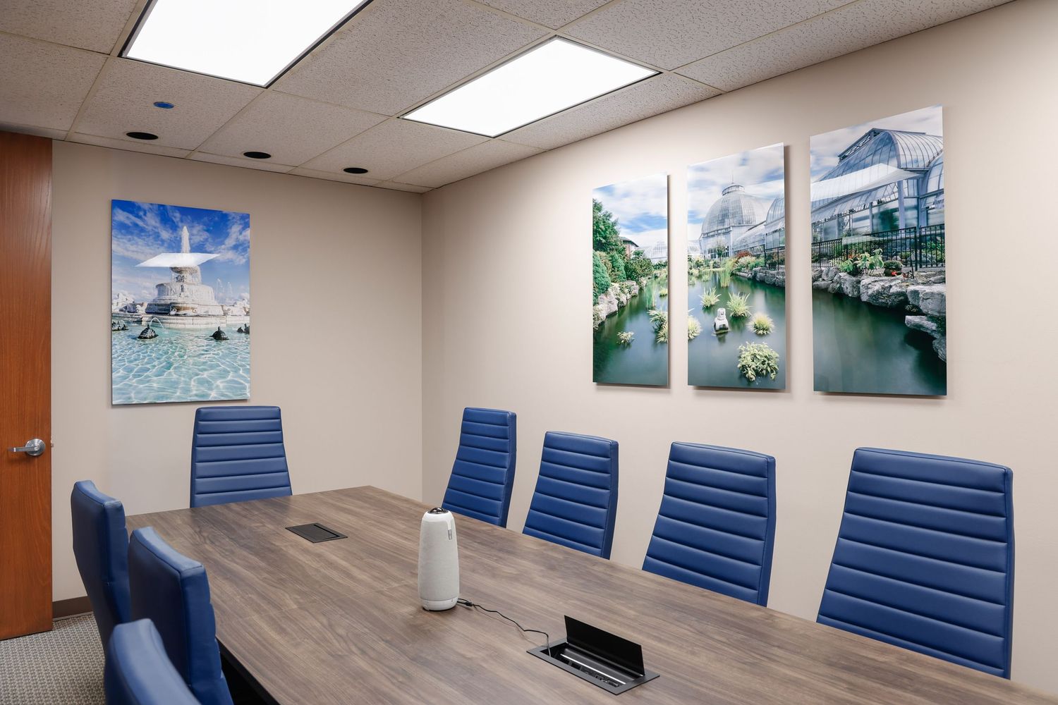 Corporate conference room with blue chairs and Detroit Belle Isle photos printed on metal displayed on walls.