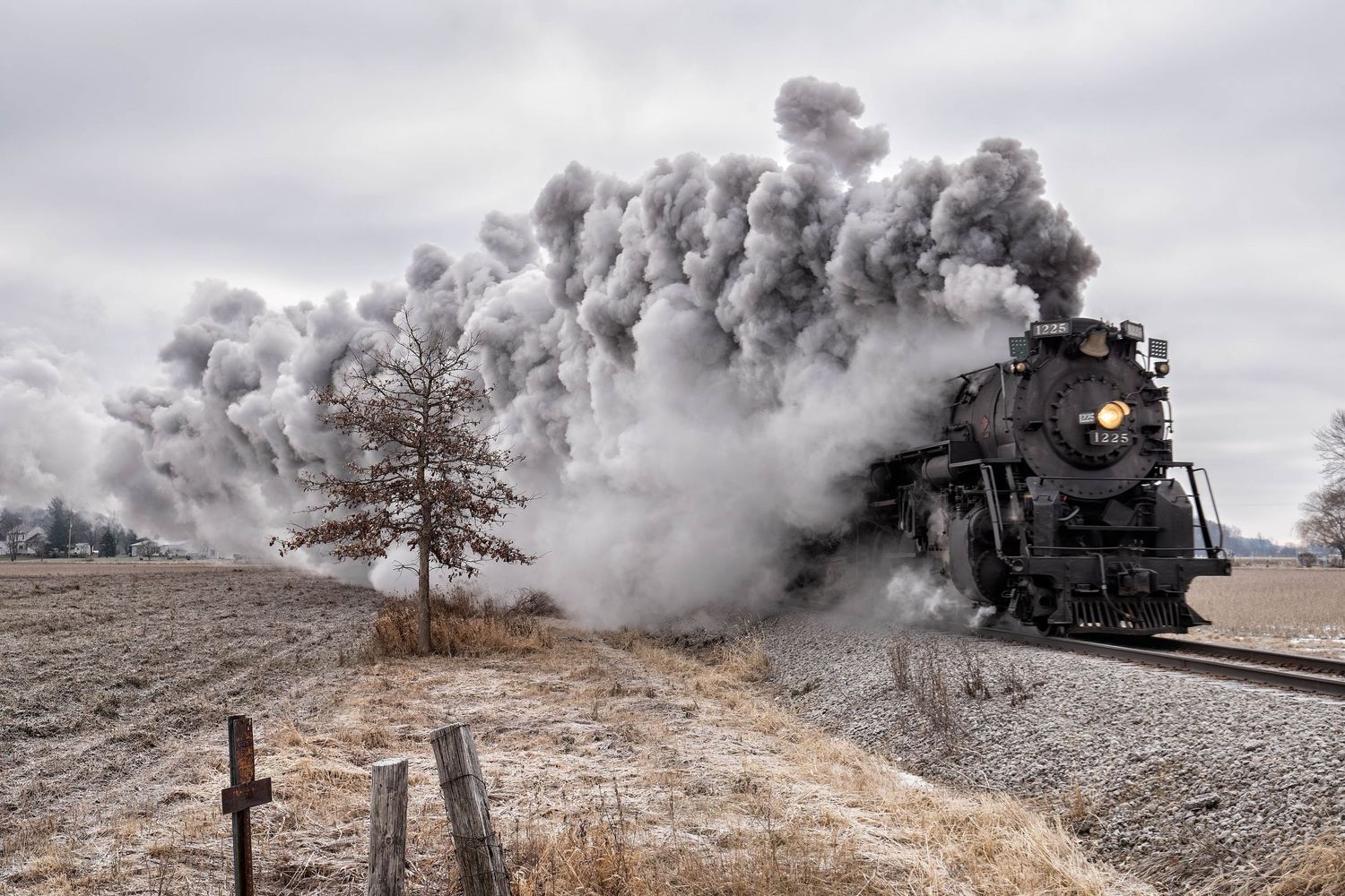 Pere Marquette 1225 steam engine creates massive cloud of steam while traveling through winter landscape.