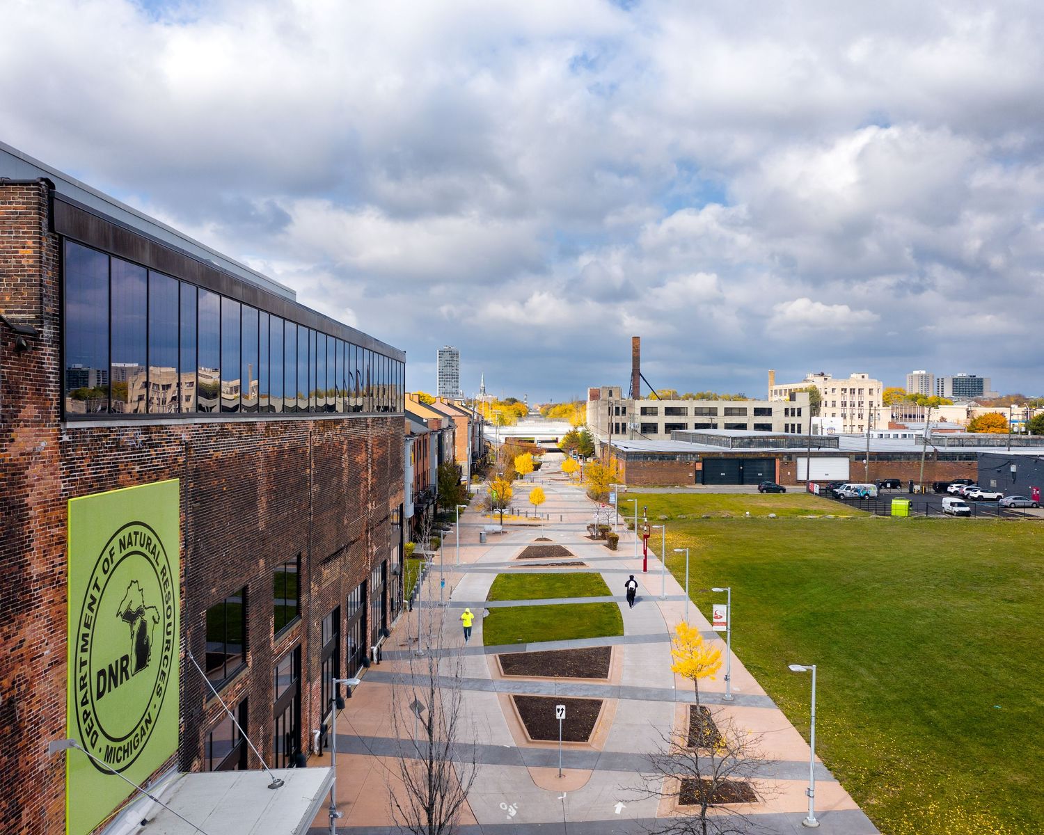 The Discovery Center building along the Dequindre Cut greenway with an overcast sky and people on the path.