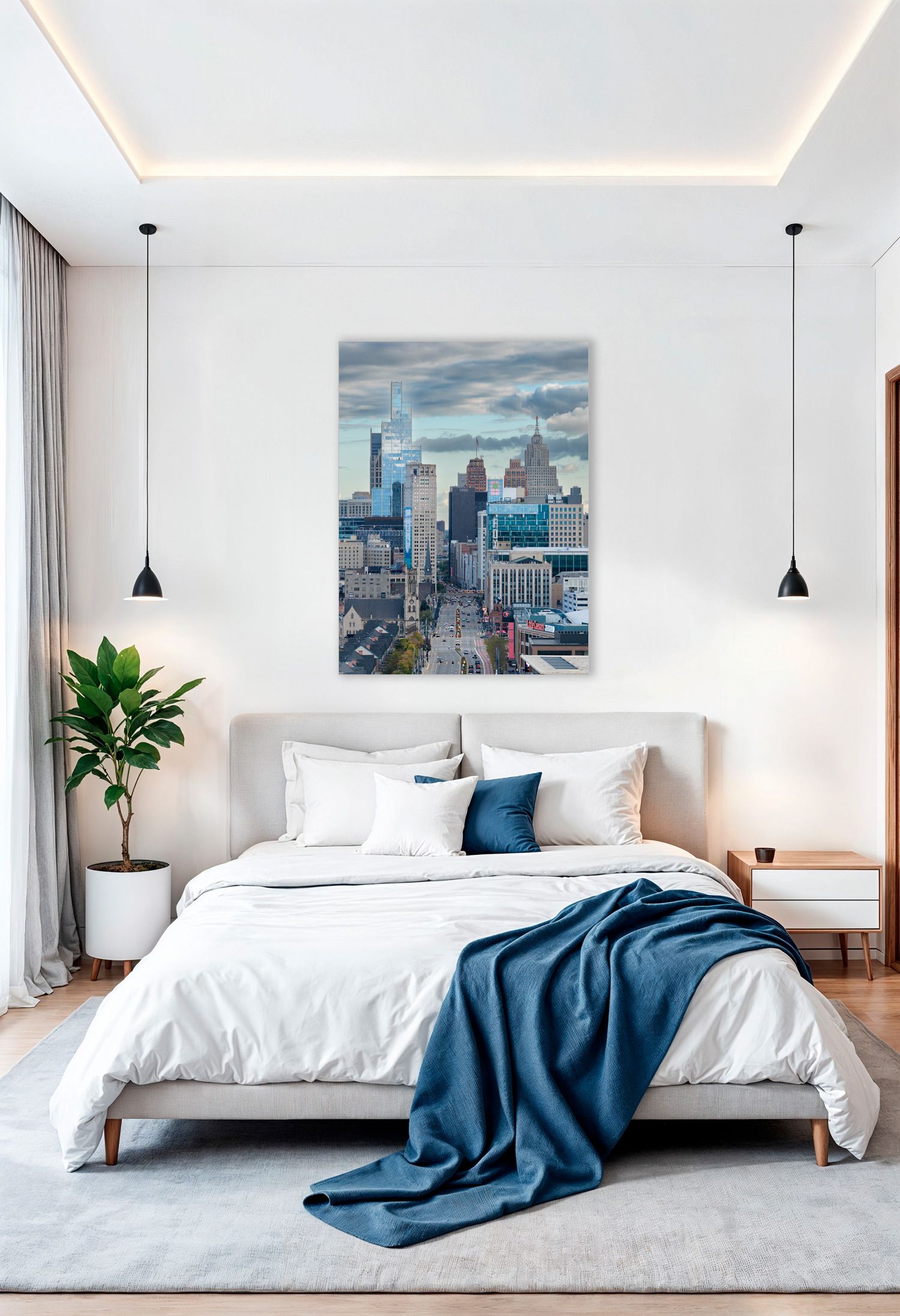 Modern bedroom interior with white bedding and a blue throw blanket, with Detroit skyline photo hanging over the bed's headboard.
