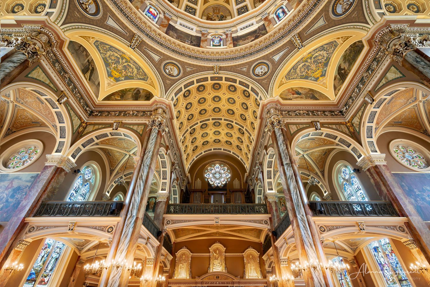 Ornate cathedral ceiling of MIlwaukee's Basilica of St Josaphat church with detailed religious artwork in a panoramic view.