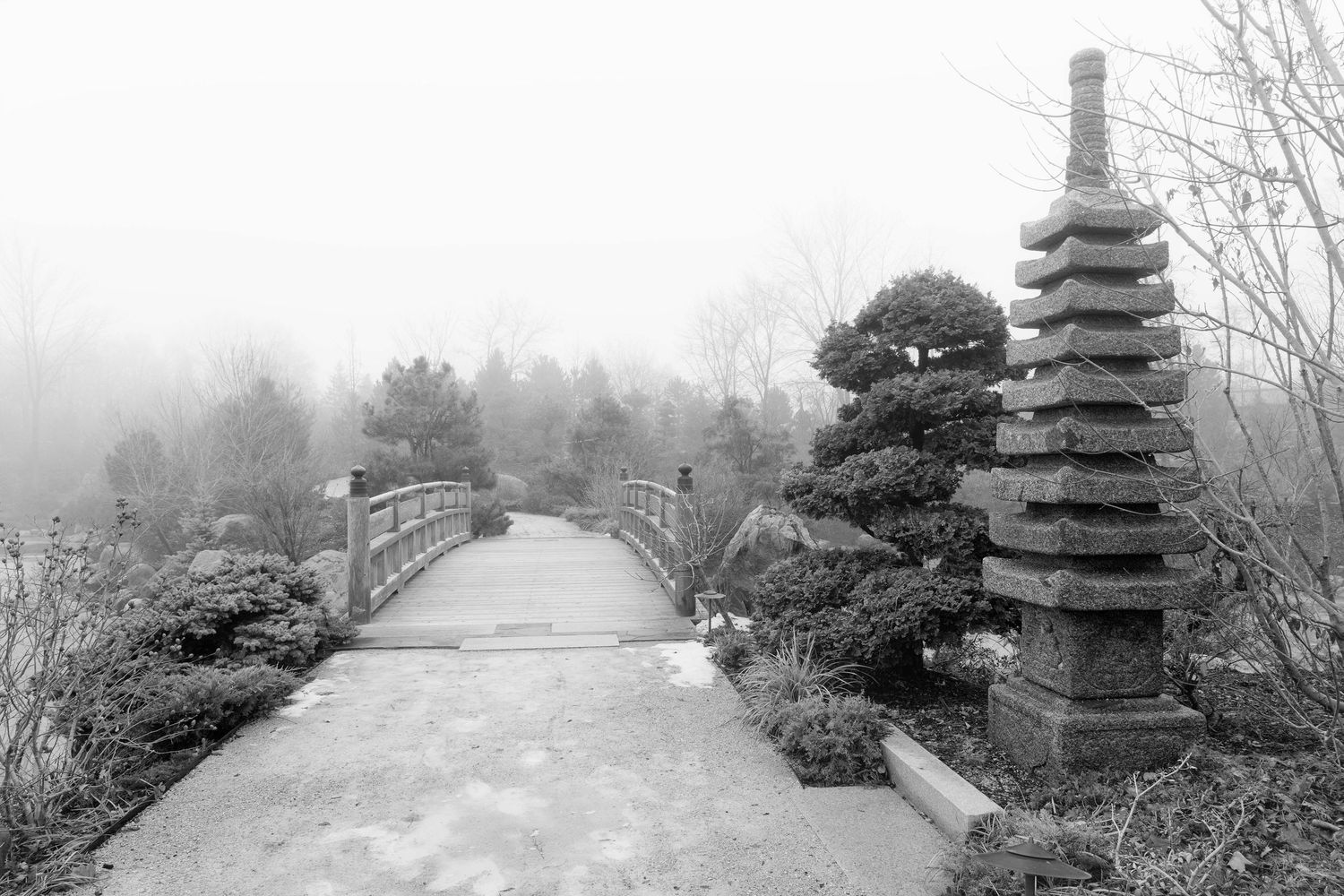 Japanese stone pagoda and arched bridge in a foggy garden landscape at the Frederick Meijer Gardens in Grand Rapids, Michigan.