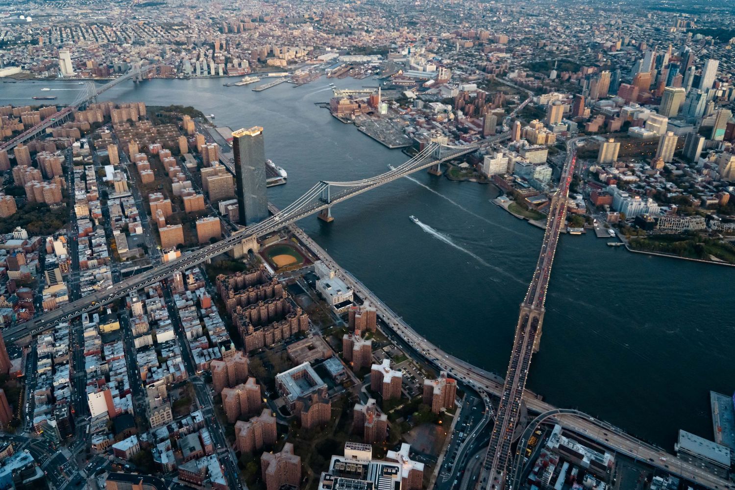 Helicopter view of Manhattan showing bridges, waterways and urban grid pattern of historic buildings.