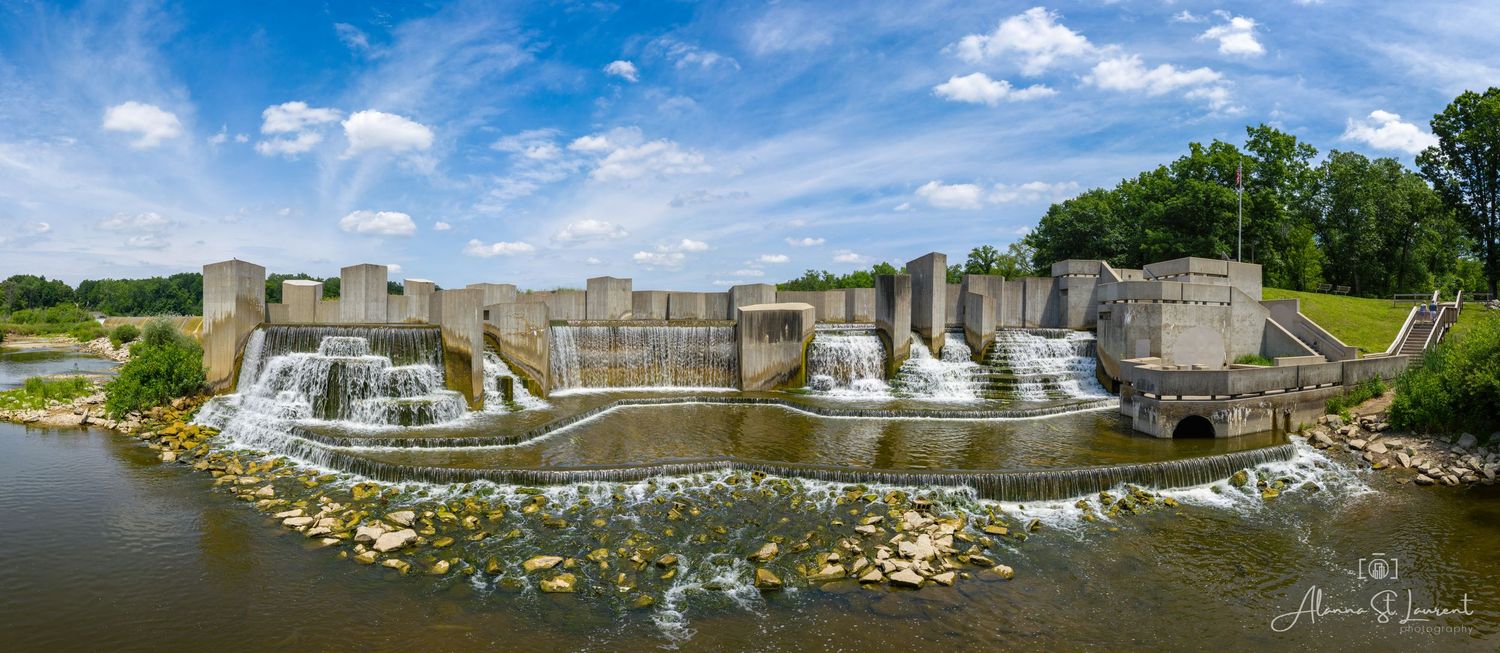 Wide panoramic view of at the Flint Stepping Stone Falls with cascading water under a bright blue sky captured by drone.
