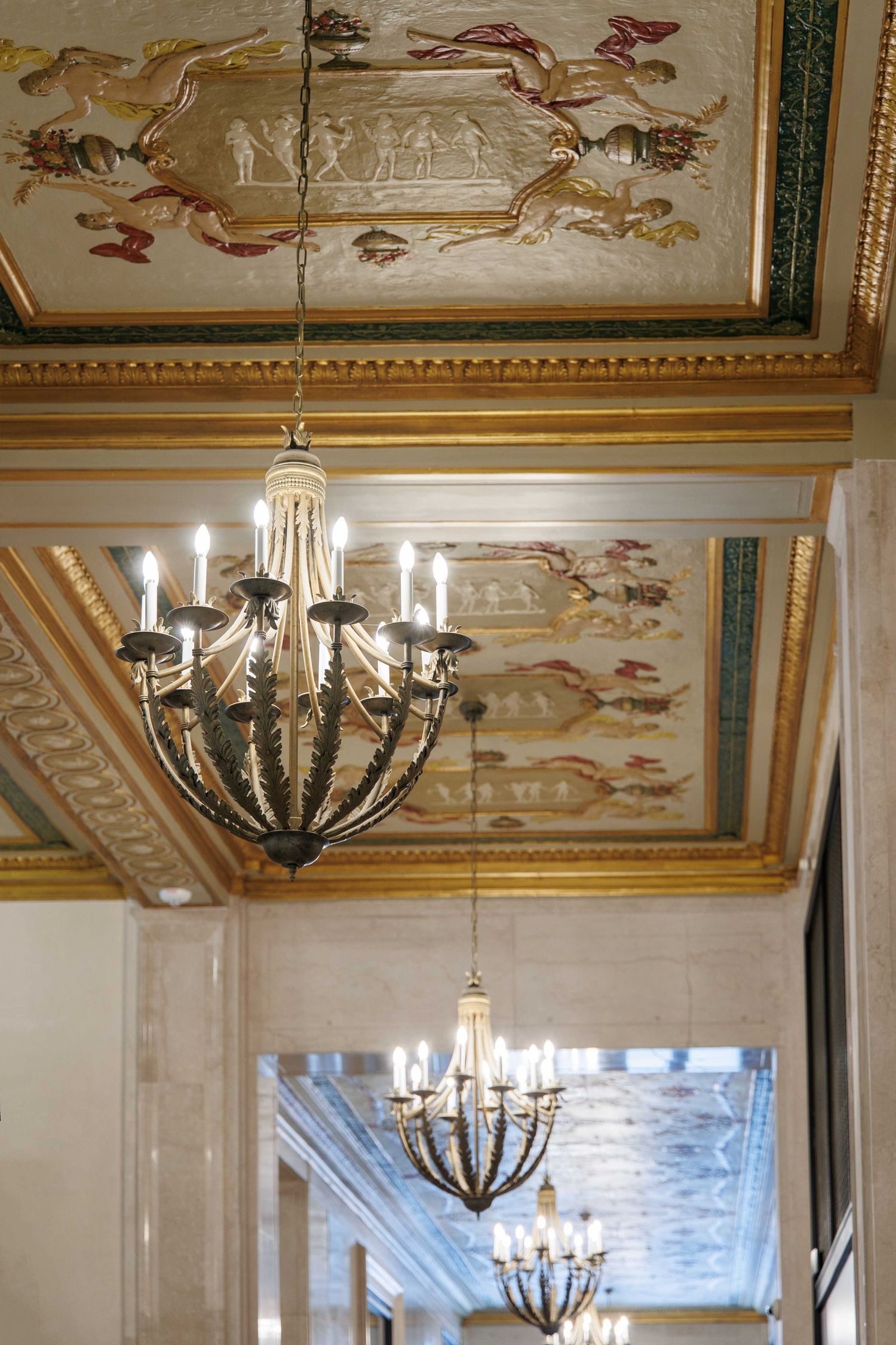 Ornate ceiling with painted murals and elegant chandeliers in in the Book Tower building in downtown Detroit, Michigan.