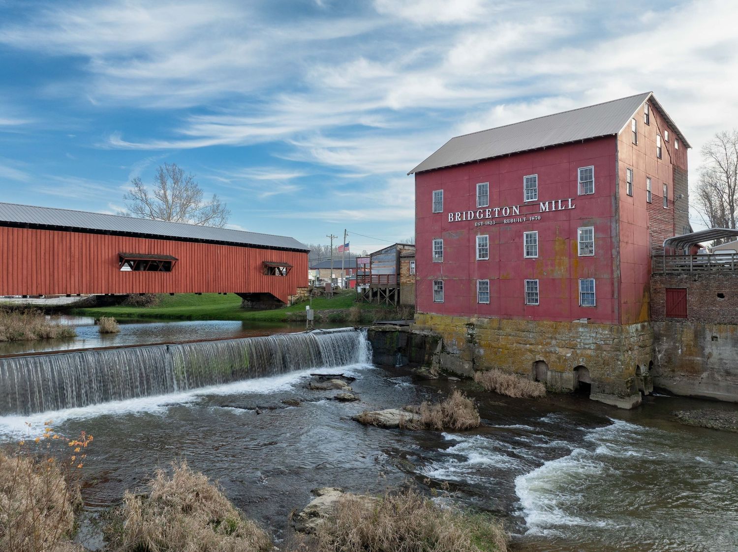 The historic Bridgeton Mill and covered bridge with a waterfall and stone foundation along the Big Raccoon Creek in rural Indiana.