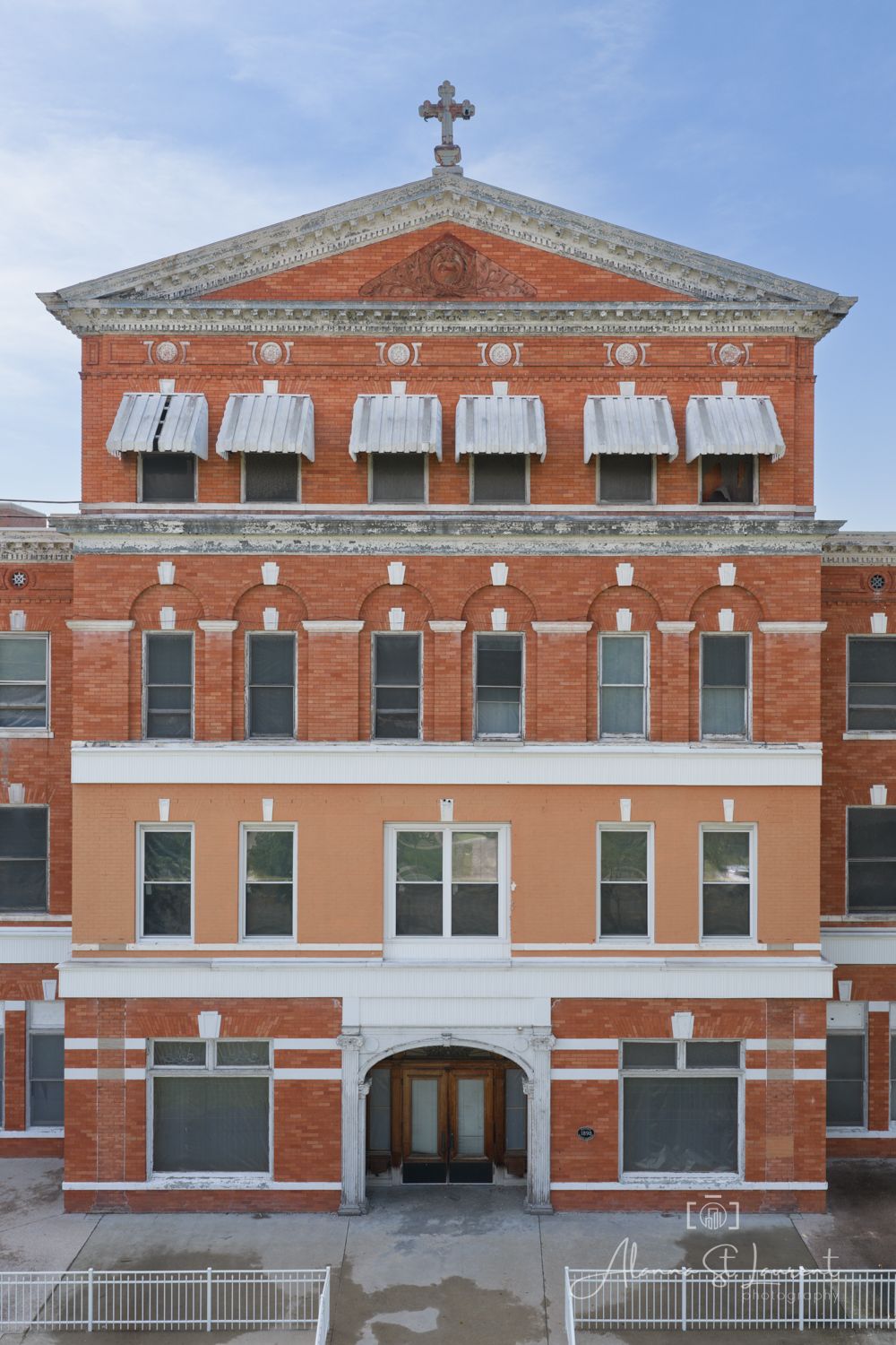 Historic red brick building with cross atop triangular pediment, arched windows, and ornate facade details.