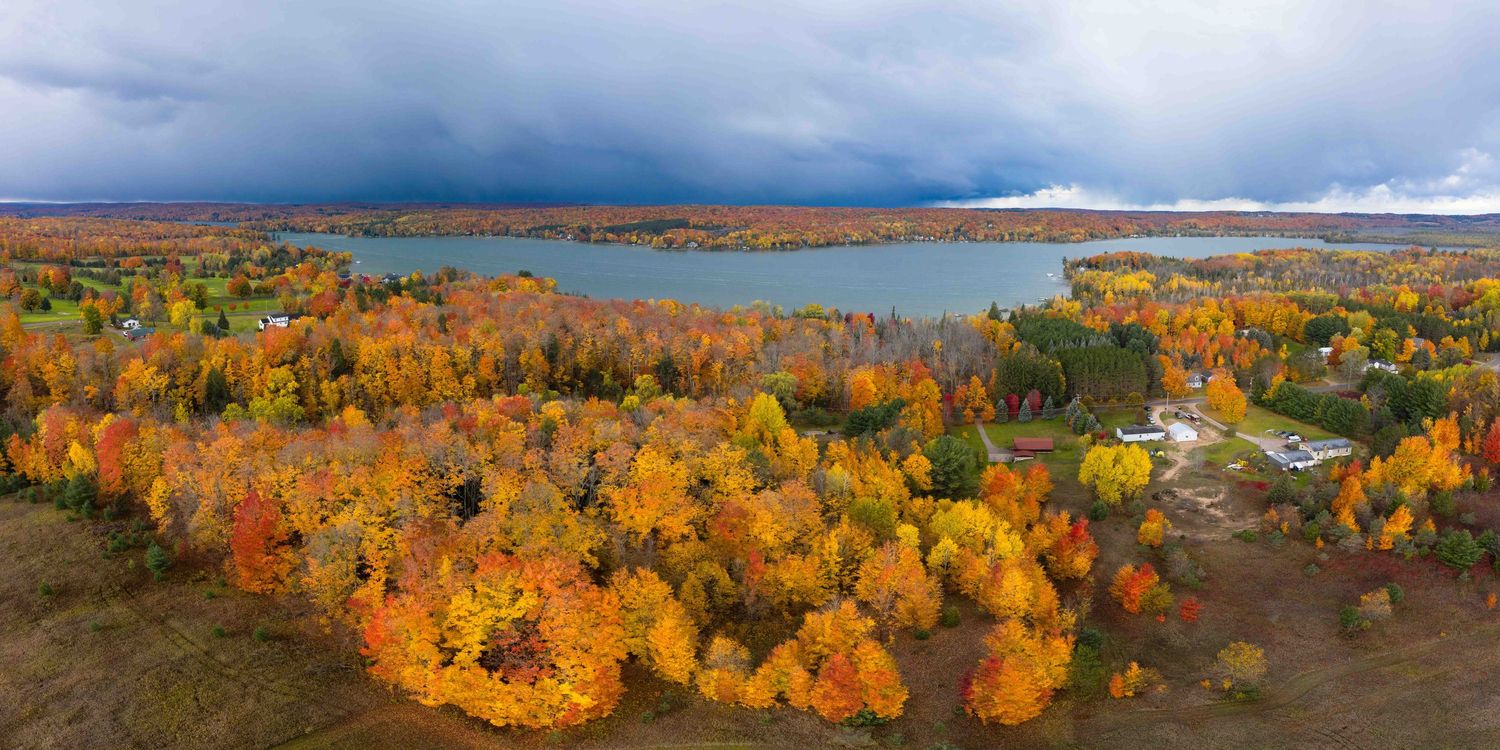 Panoramic coastal view with dramatic storm clouds and autumn-colored forest outside Petoskey and Walloon Lake in Michigan.