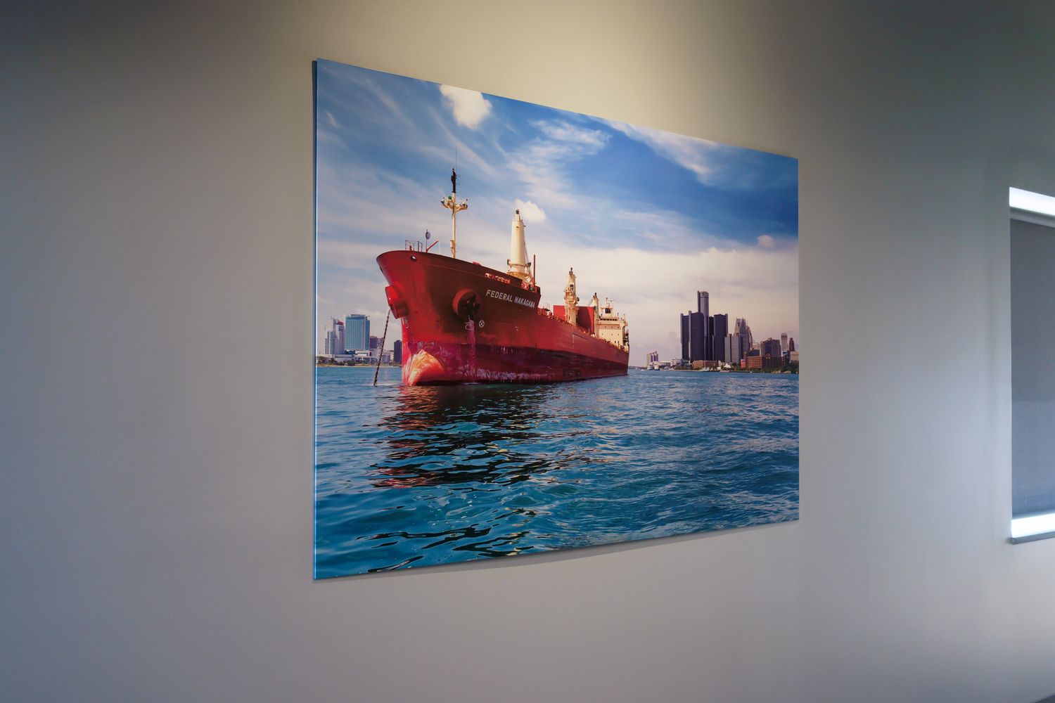 Framed photo featuring the Federal Nakagawa freighter on the Detroit River with Detroit in the background in an office setting.