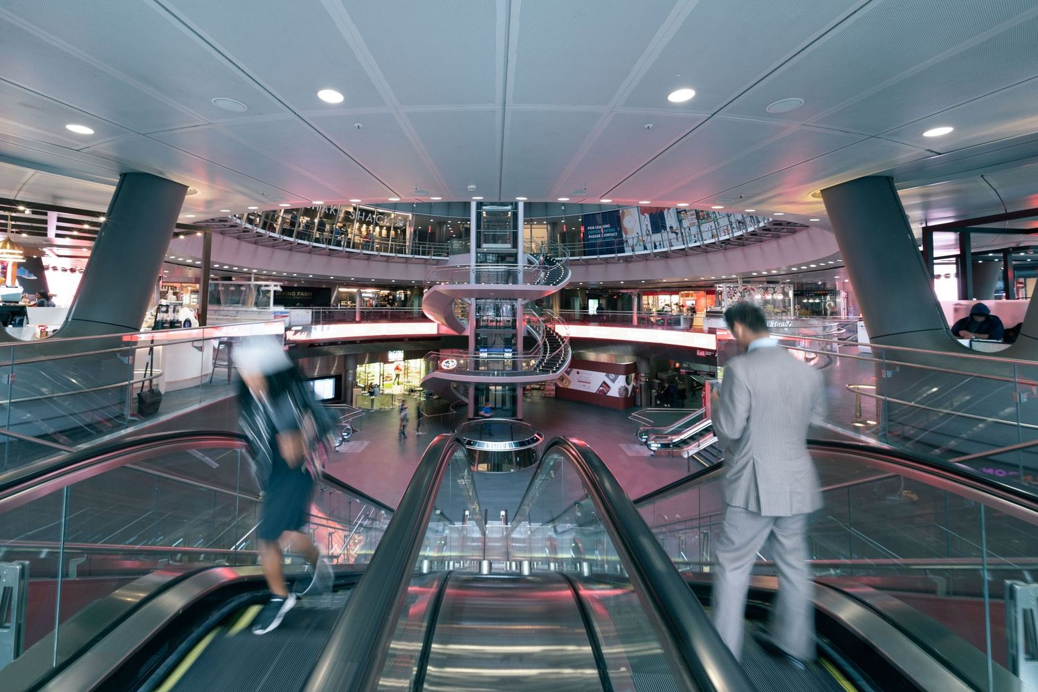 Fulton Street subway station in Manhattan with man in suit on escalator and boy with reflective surfaces creating futuristic atmosphere.