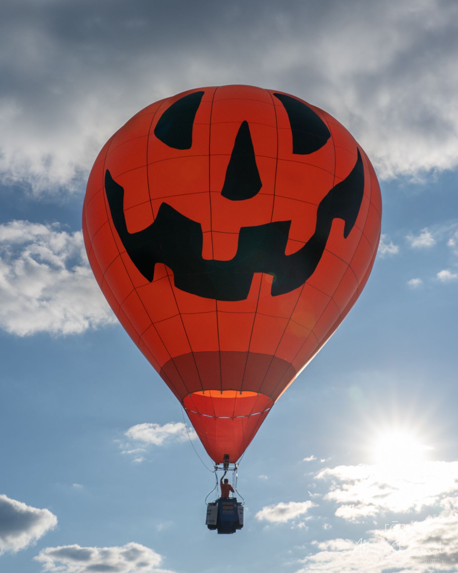 Jack-o'-lantern themed hot air balloon floating in cloudy sky during the Metamora Hot Air Balloon festival in Metamora, Michigan.
