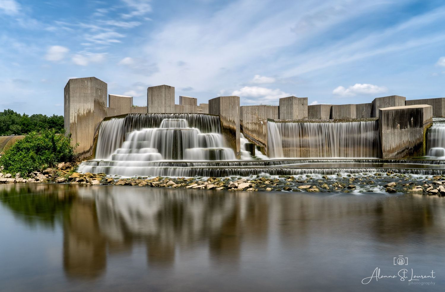 Architectural dam structure creates dramatic waterfall effect over concrete walls into calm waters below at the Flint Stepping Stone Falls.