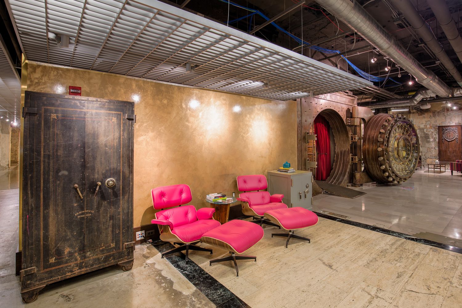 Chrysler House basement area with pink lounge chairs next to an old safe.