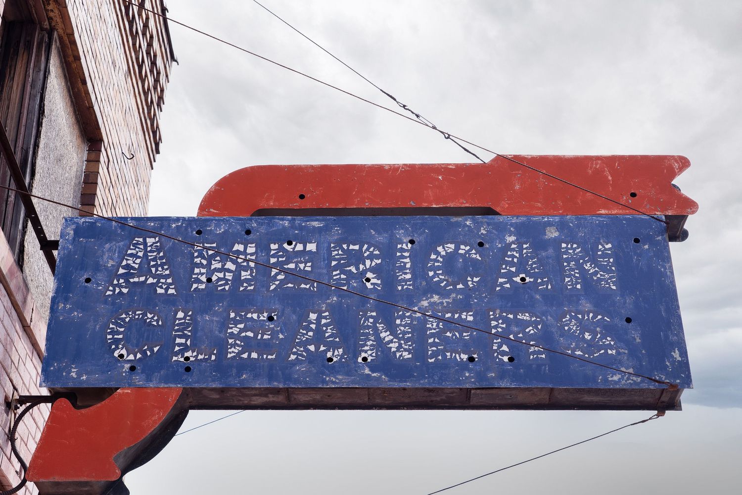 Weathered American Cleaners sign with faded blue and red paint in Saginaw, Michigan.