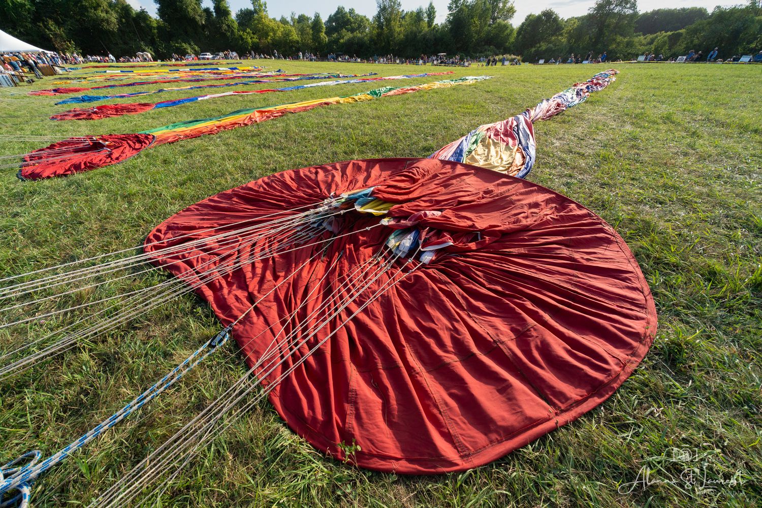 Red hot air balloon fabric spread across green grass during inflation process during the Metamora Hot Air Balloon festival in Metamora, MI.