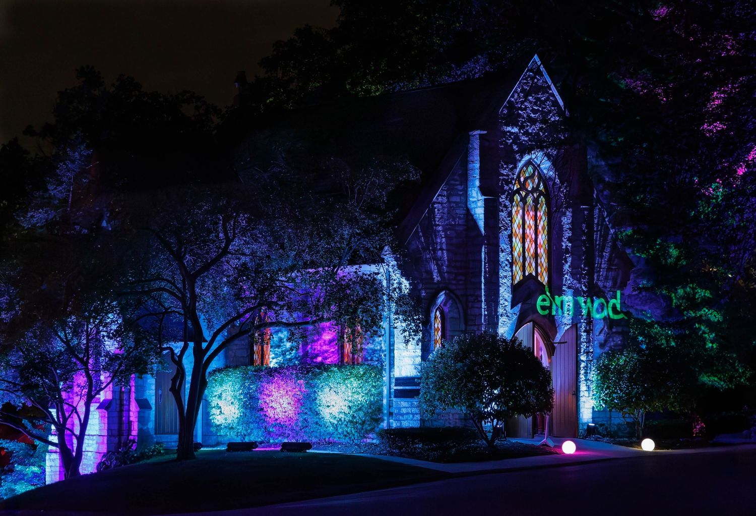 The Elmwood Cemetery chapel lit with colorful lights creating a magical nighttime atmosphere during the Elmwood Alight event in 2025.