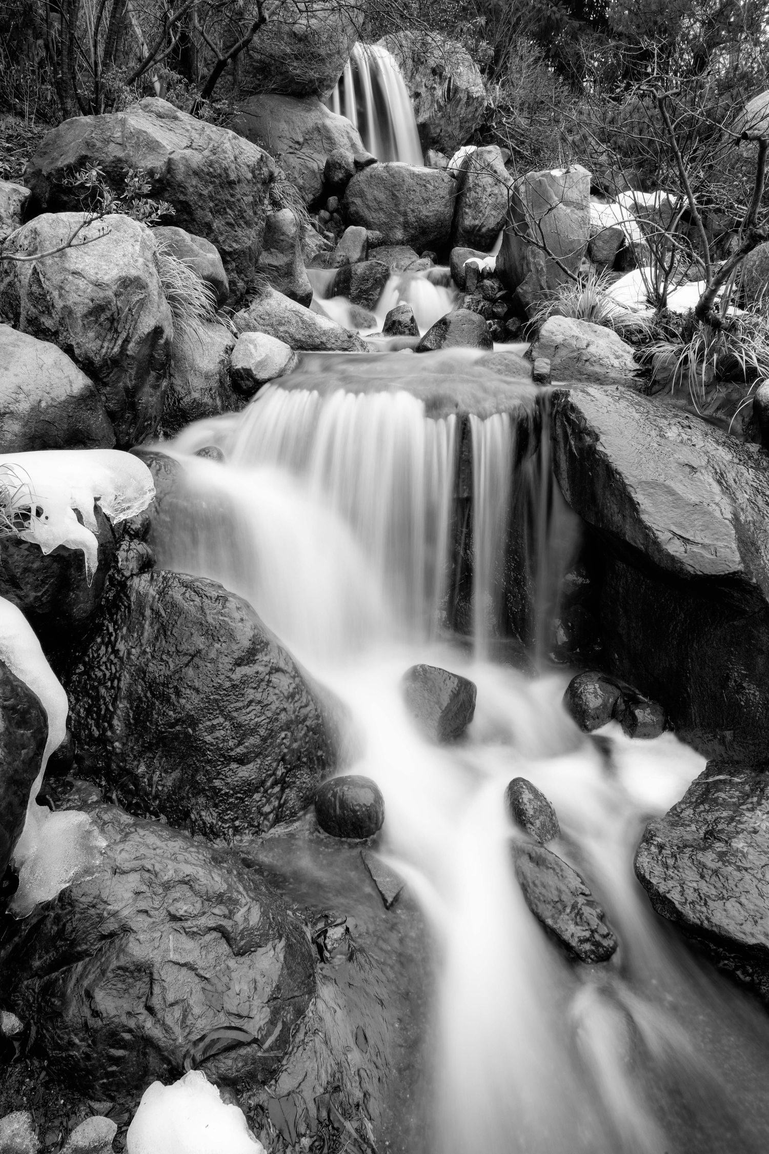 Long exposure waterfall cascading over rocky terrain in black and white at the Frederick Meijer Gardens in Grand Rapids, Michigan.