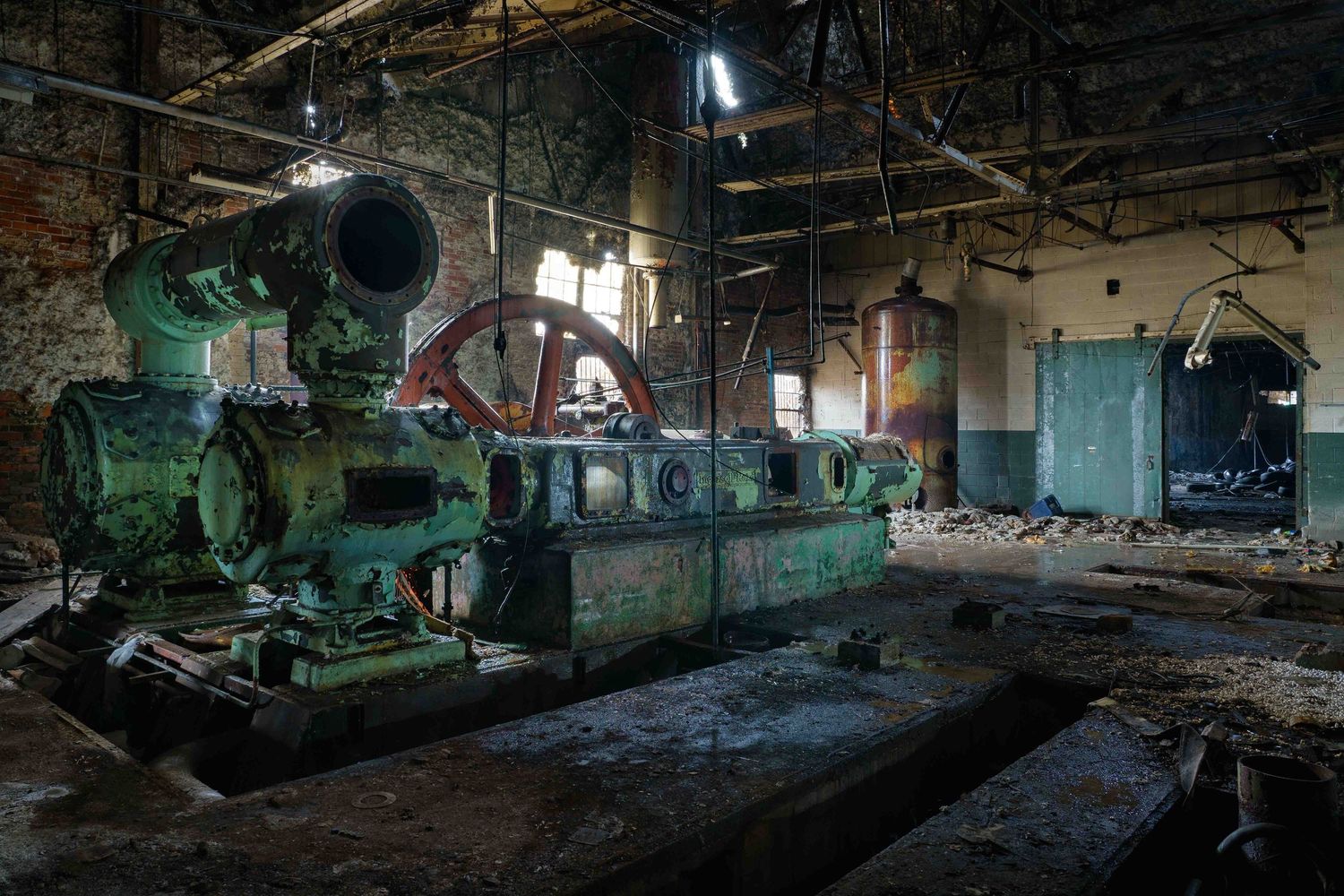 Dark interior panorama of the abandoned Cadillac Stamping plant machinery in Detroit letting in streams of light.