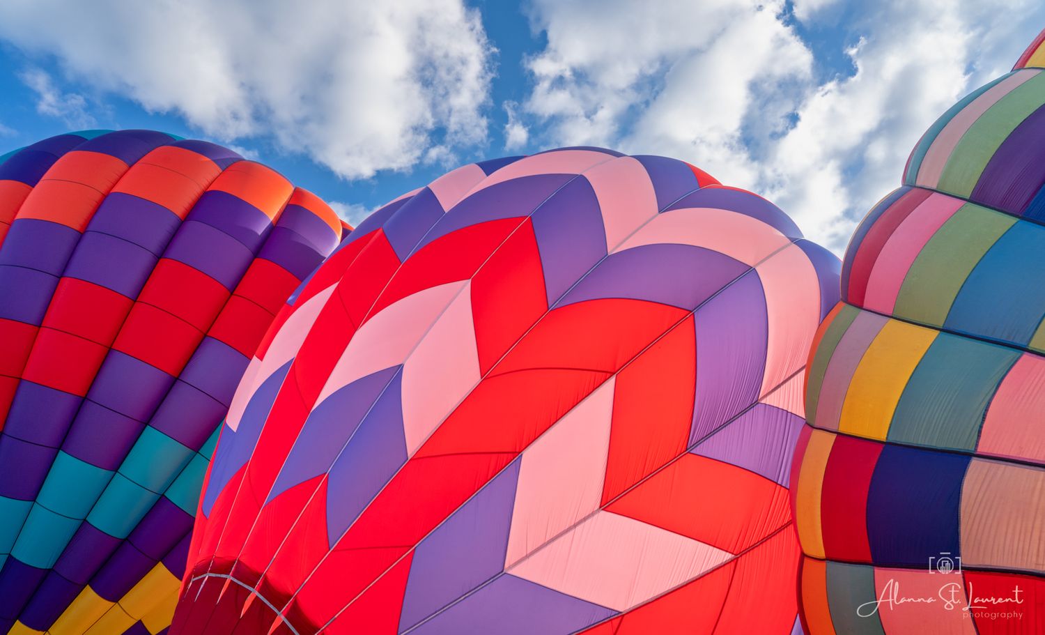 Vibrant pattern of multicolored hot air balloons photographed from below against blue sky during the Metamora Hot Air Balloon festival.