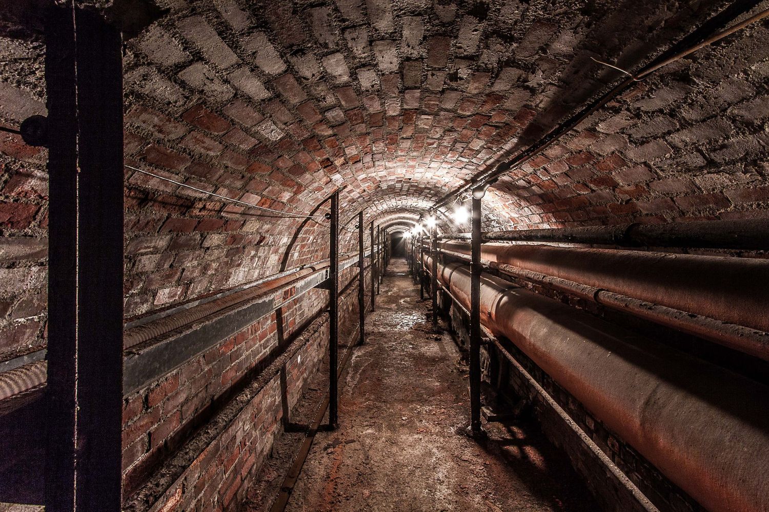 Underground brick tunnel system with arched ceilings and utility pipes at the Chrysler House in Detroit, Michigan.