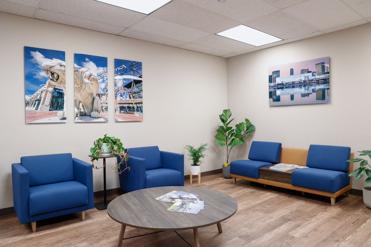 Modern law office lobby with blue sofas and chairs with Detroit photography by Alanna St Laurent on the walls.