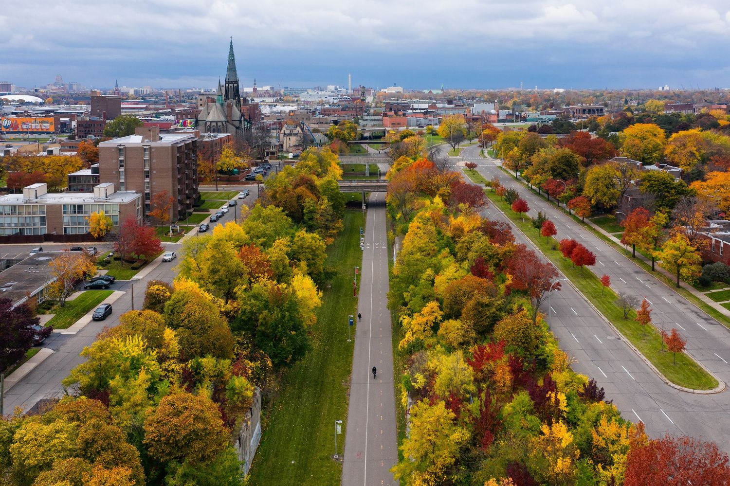 Aerial view of the Dequindre Cut greenway showing tree-lined paths and urban buildings during autumn season in Detroit, Michigan.