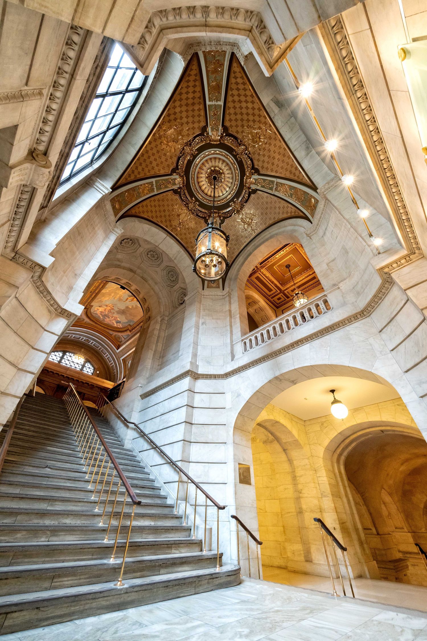 Panorama of Manhattan's New York Library elegant marble staircase with intricate architectural details and natural lighting from above.