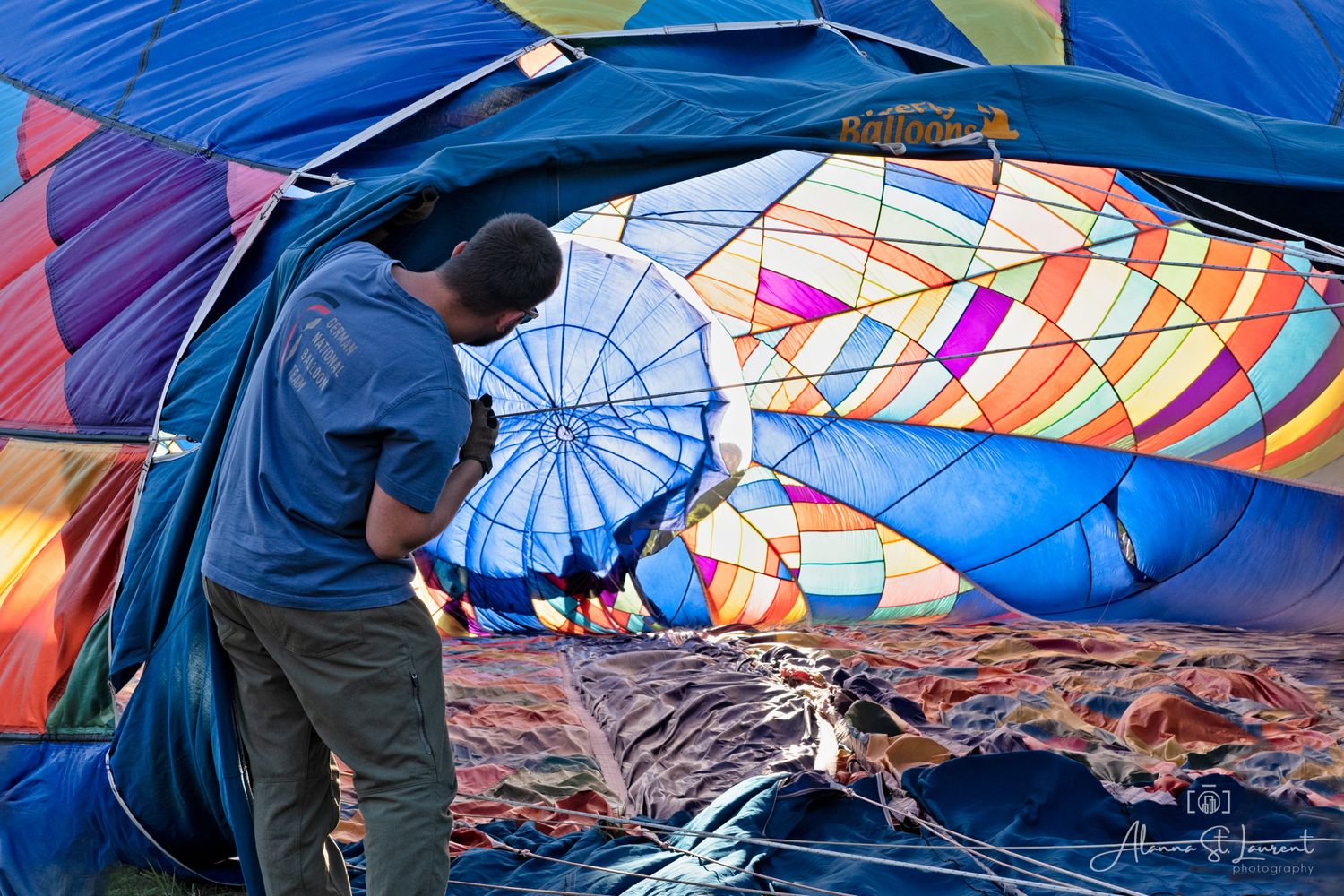 A man looks inside the hot air balloon during setup showing multicolored fabric panels during the Metamora Hot Air Balloon festival.
