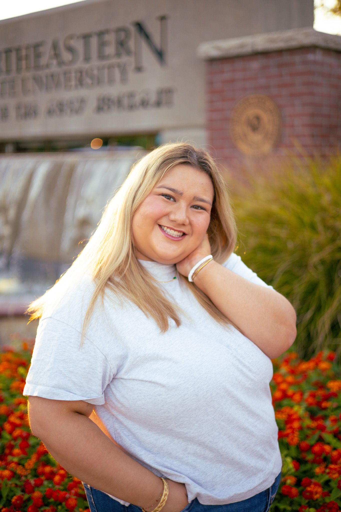 A young adult girl with a hand on her chin and is smiling.